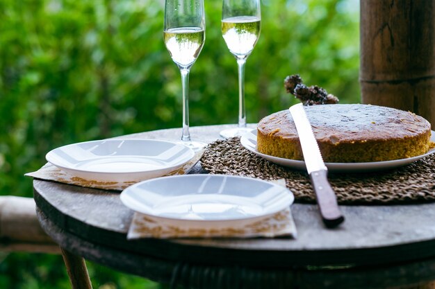 Table rustique sur balcon du chalet avec gâteau aux carottes maison, plats et deux verres à vin. Célébrer la fête, l'anniversaire, la saison d'hiver