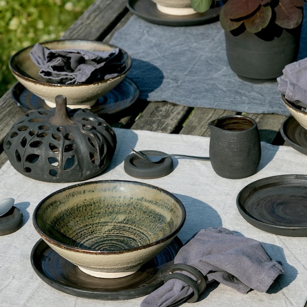 Table rustique à l'extérieur dans le jardin avec vaisselle en céramique artisanale vide