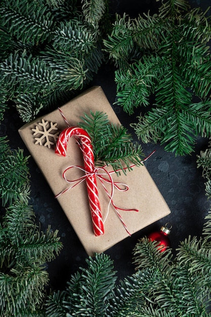 Sur la table se trouve un cadeau entouré de branches d'arbres de Noël, de jouets en bois et d'épices