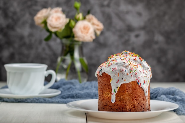 Sur la table se trouve un gâteau de Pâques fraîchement préparé avec une tasse de thé en arrière-plan