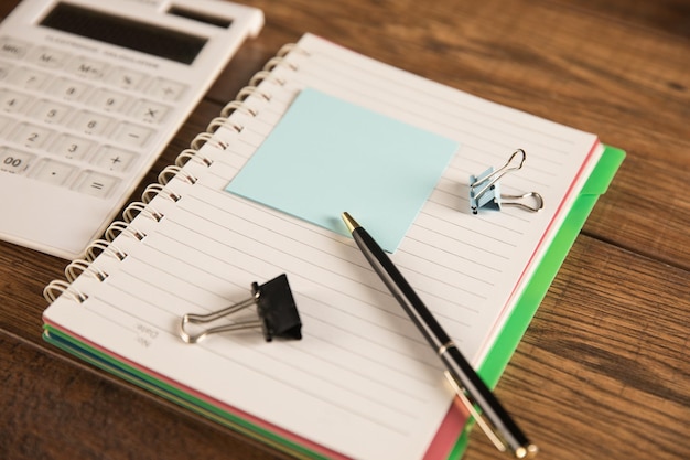 Sur la table se trouve un papier vide avec un bloc-notes et une calculatrice