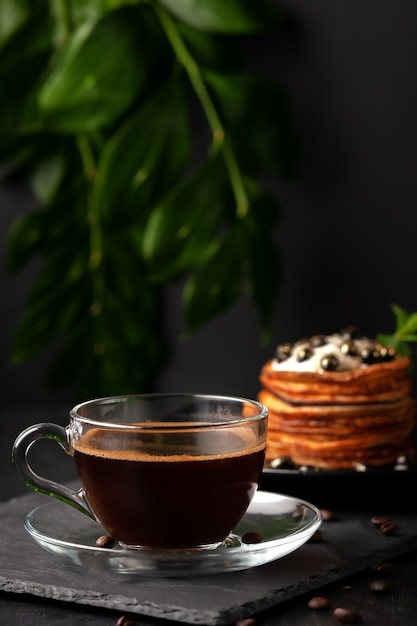 Sur la table se trouve une tasse de café parfumé fraîchement préparé avec des crêpes faites maison avec des baies fraîches