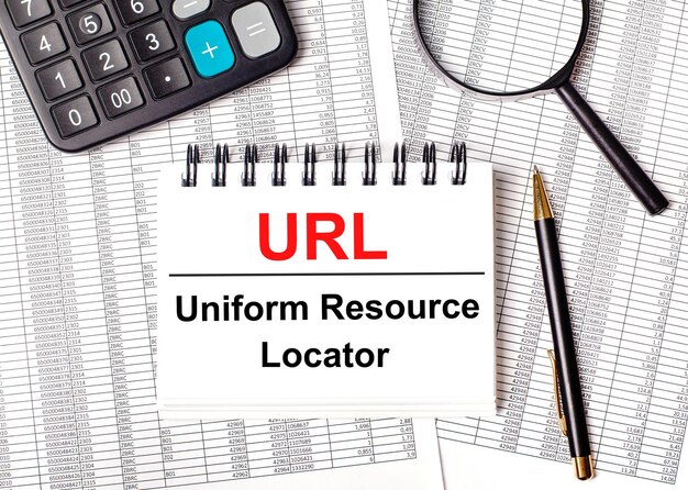 Sur la table se trouvent des rapports une loupe une calculatrice un stylo et un cahier blanc avec le texte URL Uniform Resource Locator