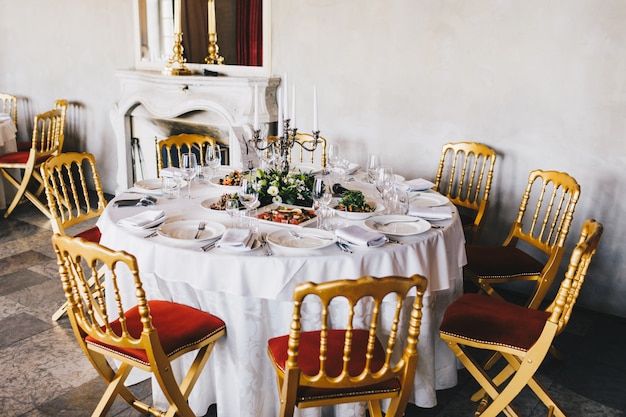 Table servie avec des plats savoureux, chandelier et couverts blancs, décorée pour une célébration de mariage dans un restaurant de luxe