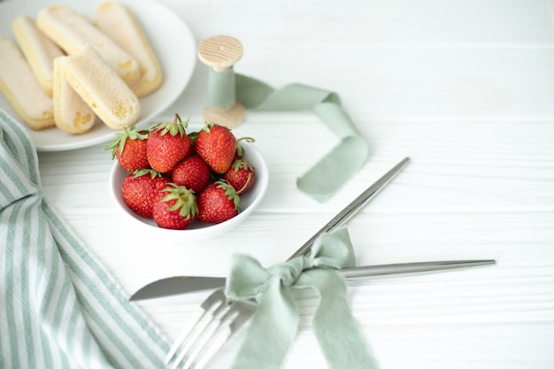 Sur la table sont des ustensiles de cuisine et une assiette avec une récolte fraîche de fraises uneassiette avec Savo