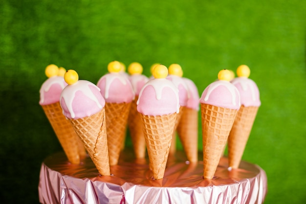 Table sucrée et belles glaces à base de corne de sucre et de glaçage rose et blanc.