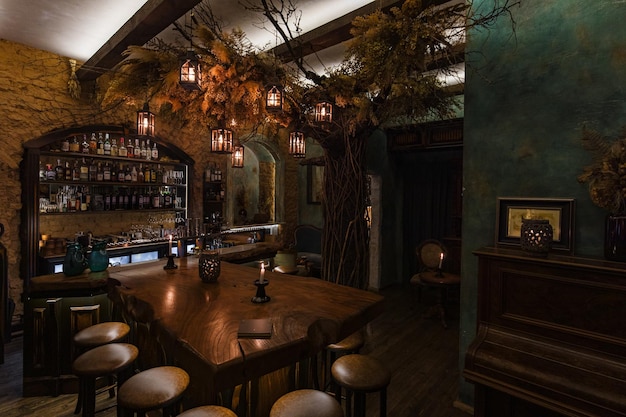 Table et tabourets rustiques sous l'arbre avec des lanternes dans un pub