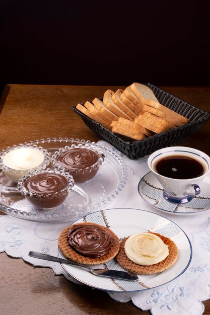 Table avec tasse de café avec toast et tartinade de chocolat chocolat blanc et angle de tartinade aux noisettes sur table en bois portrait