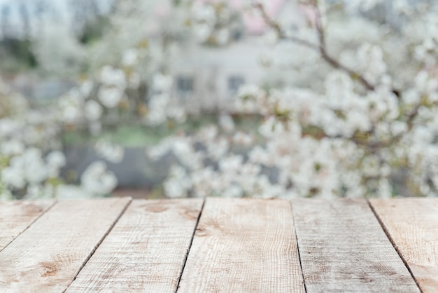 Table de terrasse en bois vide avec feuillage et fond d'arbre en fleurs blanc