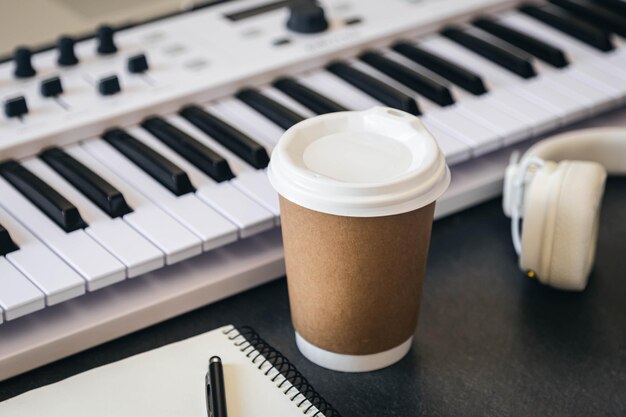 Table de travail de musicien avec tasse en papier et clavier de piano blanc