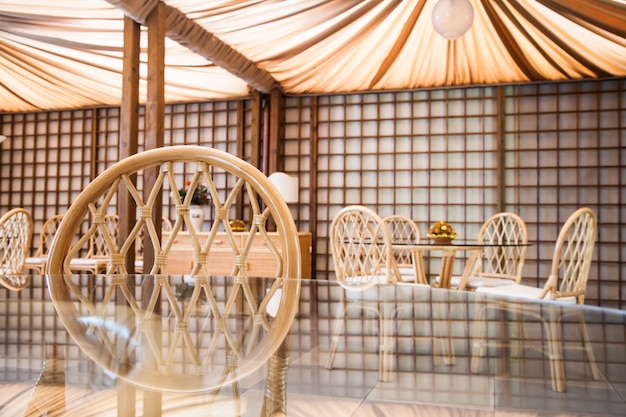 Table en verre avec chaises en osier dans un intérieur élégant