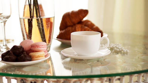 Table en verre avec une tasse de café, croissants sucrés. Une photo festive et romantique. Matin après da