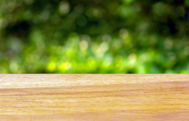 Table vide de planche en bois devant le fond vert de bokeh pour l'affichage du produit