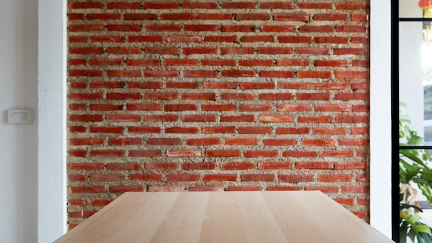 Table vide de planche de bois avec un fond de mur de briques rouges