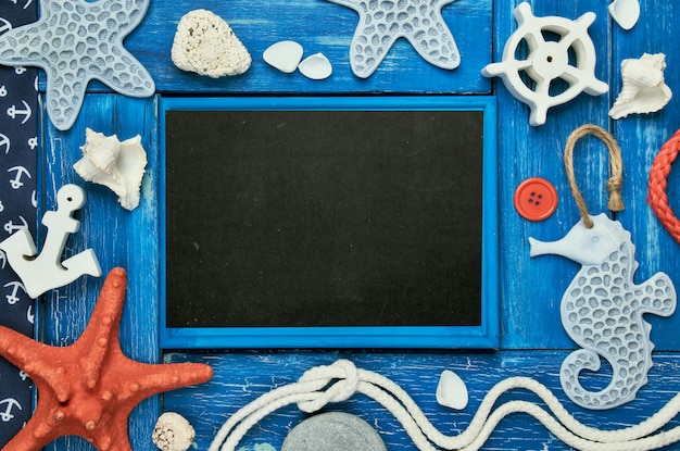 Tableau blanc avec coquillages, pierres, corde et étoile de mer sur fond en bois bleu, espace copie