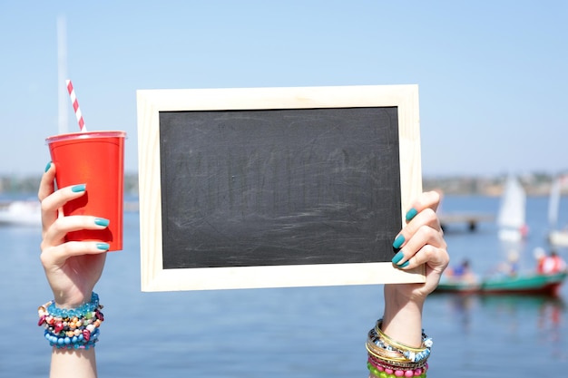 Photo tableau blanc dans la main féminine sur fond de plage