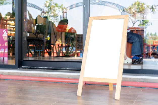 Photo un tableau blanc est debout sur un stand en bois à l'extérieur d'un restaurant