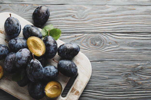 Tableau blanc avec des prunes fraîches sur bois