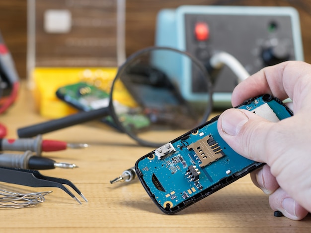 Le tableau bleu d'un téléphone portable est entre les mains d'un homme.