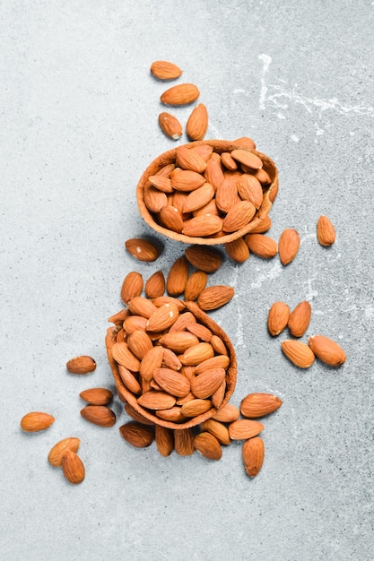 Tableau avec un bol d'amandes sur un fond de pierre claire Snacks sains Noix