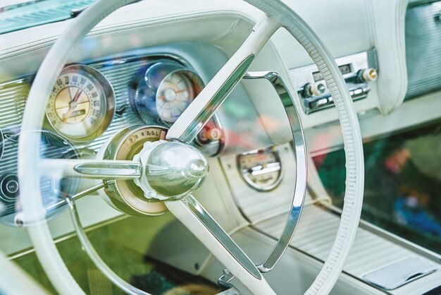 Tableau de bord intérieur lumineux de voiture rétro et volant avec commandes dans une voiture américaine classique