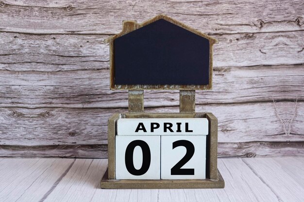 Photo tableau à craie avec la date d'avril sur un cube blanc sur une table en bois