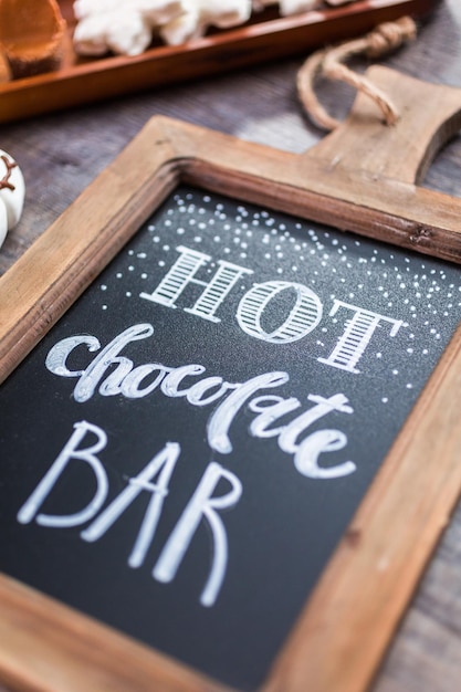 Photo tableau à craie avec signe pour barre de chocolat chaud avec une variété de garnitures.