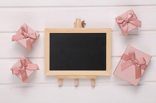 Tableau de craie vide et coffrets cadeaux sur une table en bois blanc