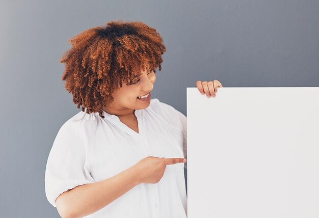 Photo tableau de femme noire et bannière avec maquette et marketing placement de produit et marque sur fond de studio affiche espace blanc et femme pointant avec sourire publicité et image de marque et promotion