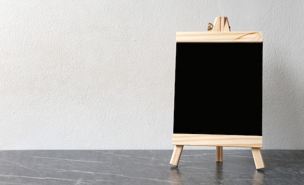 Photo tableau de menu en bois noir blanc, tableau noir, debout sur un mur de ciment blanc