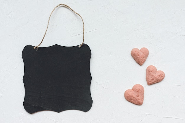 Tableau noir et biscuits en forme de coeur sur fond blanc