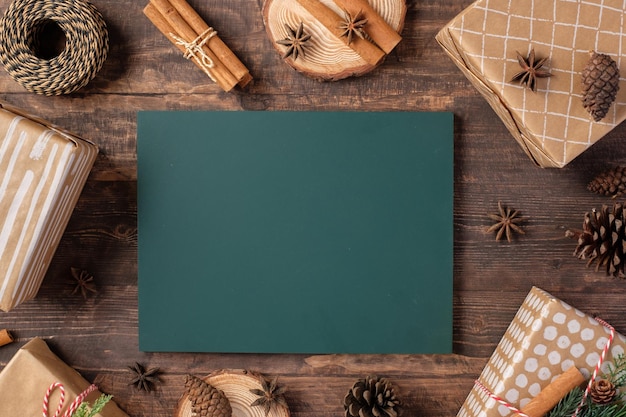 Tableau noir avec boîte-cadeau de Noël et papier d'emballage kraft présent sur une table en bois marron