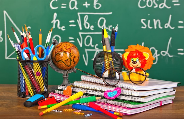 tableau noir avec boîte à crayons et matériel scolaire sur table