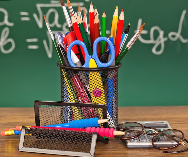 Photo tableau noir avec boîte à crayons et matériel scolaire sur table