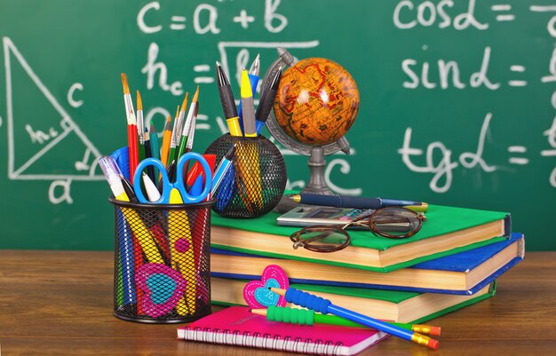 tableau noir avec boîte à crayons et matériel scolaire sur table