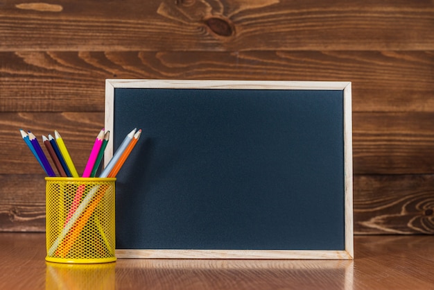 Un Tableau Noir Avec Un Espace Pour Le Texte, Un Ensemble De Crayons De Couleur Avec Un Verre Sur Un Bois