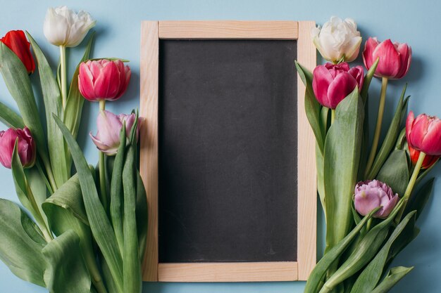 Tableau noir sur un fond bleu avec des tulipes.