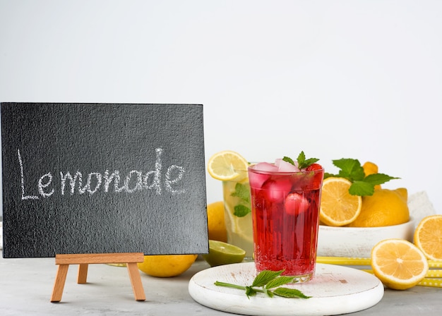 Tableau noir pour écrire une recette de boisson d'été et un verre de limonade aux fruits rouges