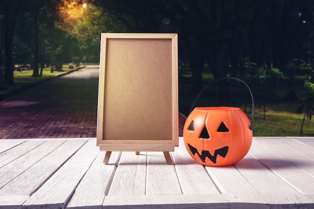 Le tableau noir sur le stand avec des citrouilles d&#39;halloween sur plancher en bois et fond noir