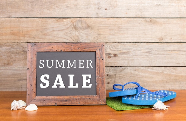 Tableau noir avec texte Summer SALE flops coquillages sur fond de bois marron