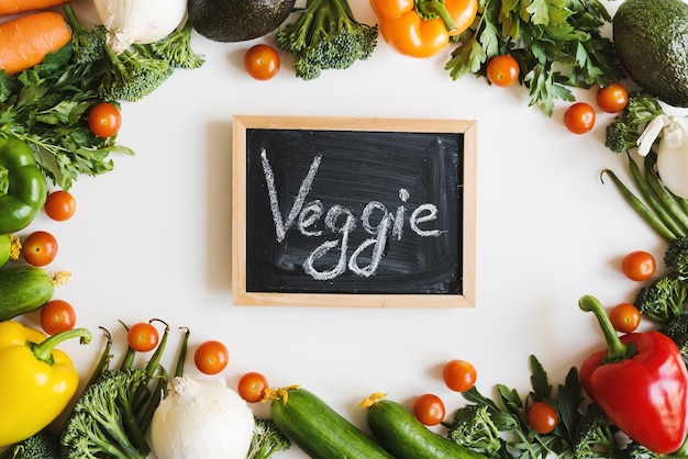 Photo tableau noir avec texte veggie sur fond blanc et cadre de légumes assortis