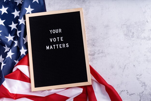 Tableau noir avec le texte de votre vote compte avec le drapeau américain sur fond de marbre blanc