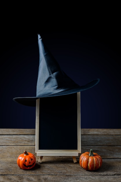 Le tableau sur le stand, chapeau de sorcière avec des citrouilles d&#39;Halloween sur un plancher en bois