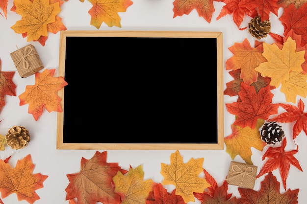 Tableau de surface en bois vue de dessus avec des feuilles d'érable colorées, cônes, coffrets cadeaux sur blanc