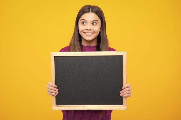 Tableau de vente de l'école une adolescente joyeuse un enfant tient un tableau noir avec un espace de copie