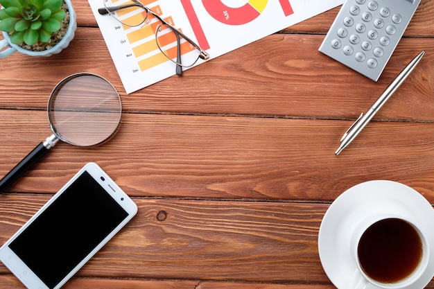 tableaux d'affaires, téléphone, calculatrice et café sur une table en bois