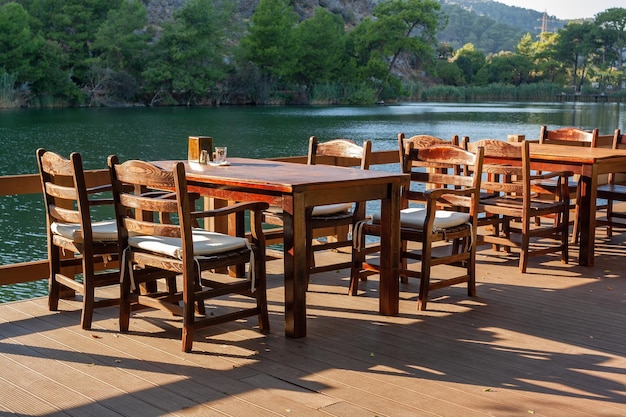 Tables vides en bois avec des chaises au restaurant sur la rive du fleuve photo horizontale
