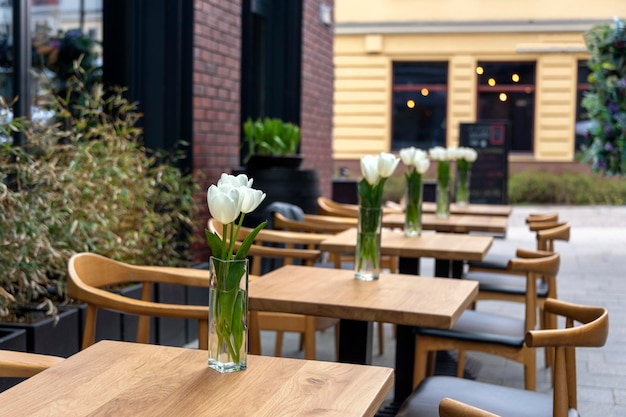 Tables vides avec des fleurs dans un café ou un restaurant en plein air Tables et chaises au café-terrasse Tulipes de cadre touristique sur la table de café