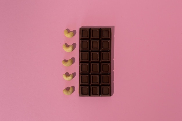 Tablette de chocolat noir aux noix de cajou sur fond rose