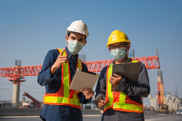 Tablette de deux ouvriers ingénieur travaillant sur la construction de routes de site, arpenteur de bâtiment de constructeur d'architecture homme asiatique professionnel